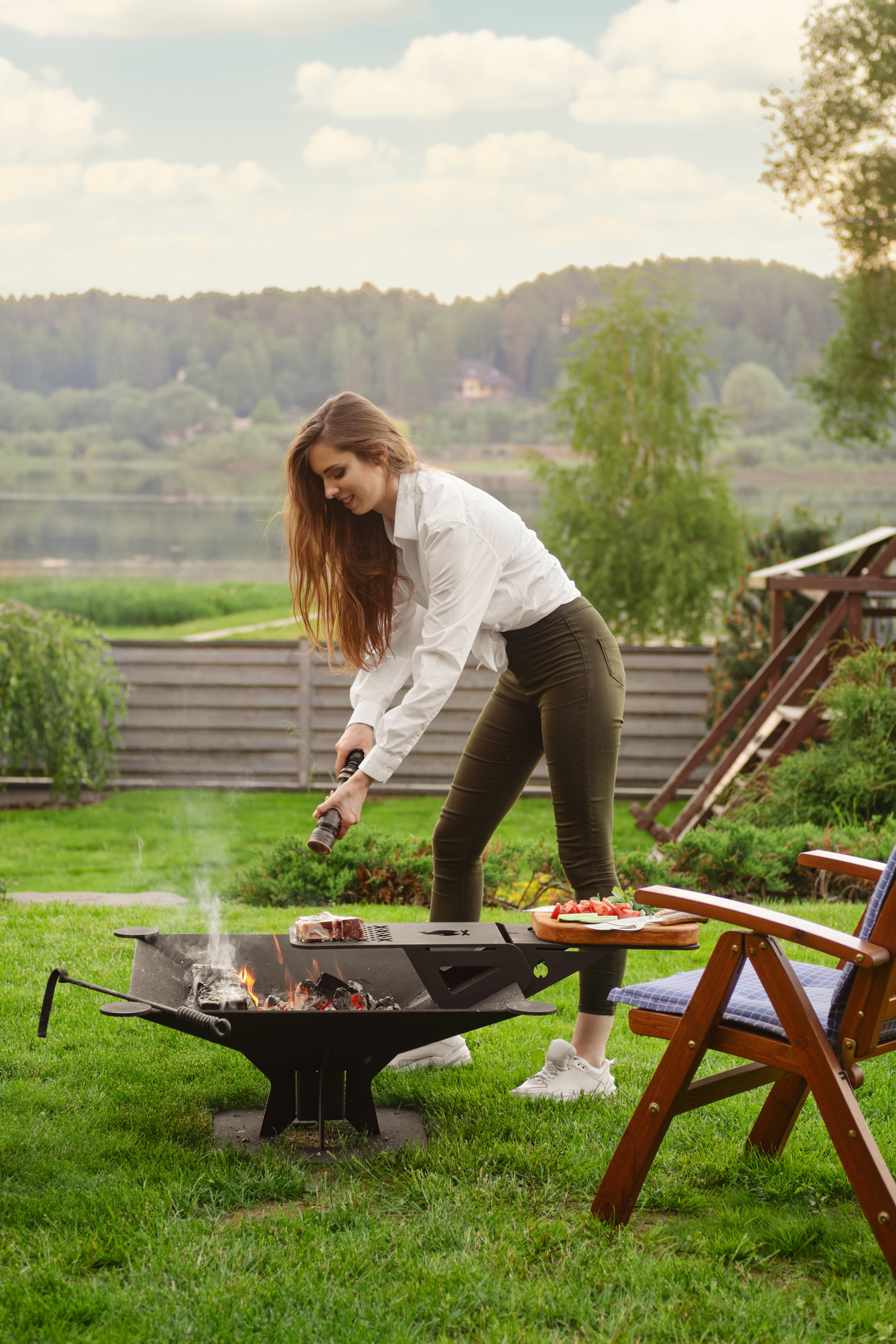 Woman seasoning steak on grill in her country house